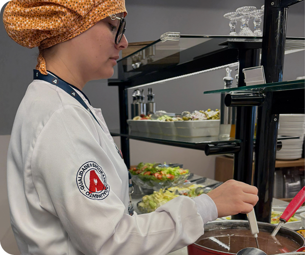 Imagem de uma profissional mendindo a temperatura de um alimento com um termômetro